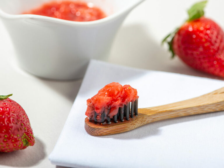 Red foods on a white backdrop and on a toothbrush