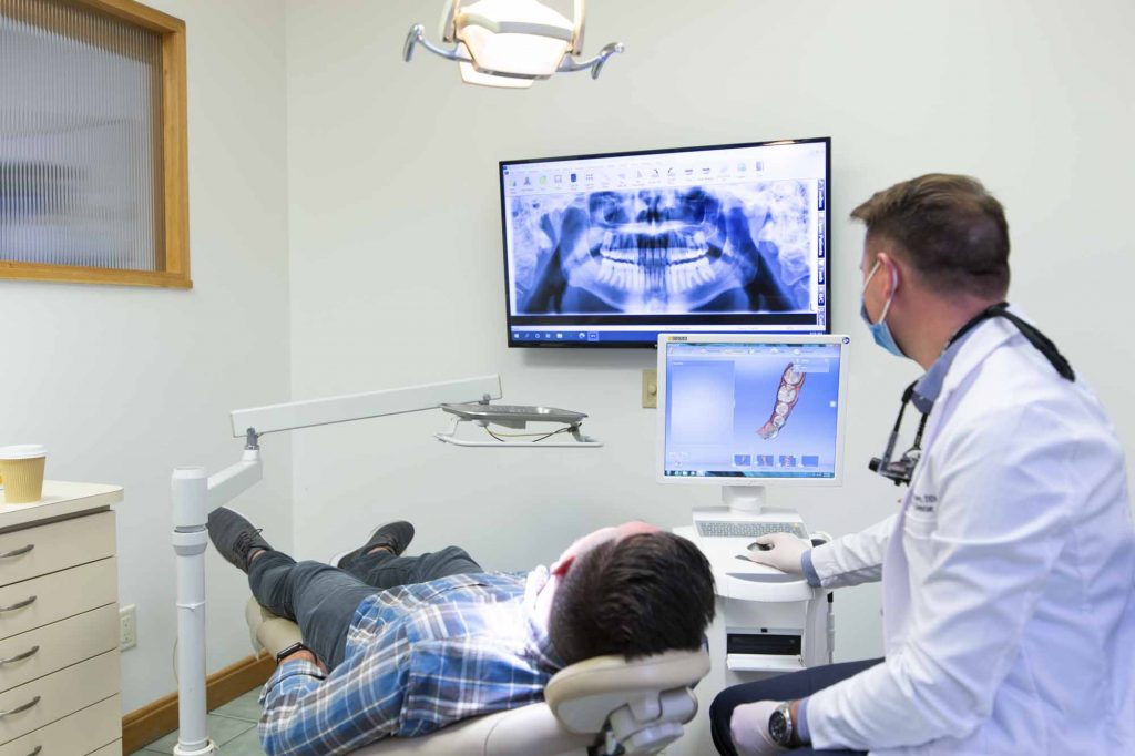 dr brant finney, a dentist at bloomington indiana, sits next to a patient and examines xray results