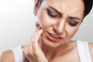 A woman experiencing jaw pain, in need of emergency dental care